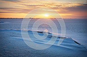 Beautiful winter landscape with frozen lake, crack and sunset