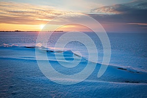 Beautiful winter landscape with frozen lake, crack and sunset