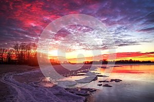 Beautiful winter landscape with frozen lake and sunset