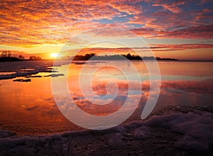 Beautiful winter landscape with frozen lake and sunset