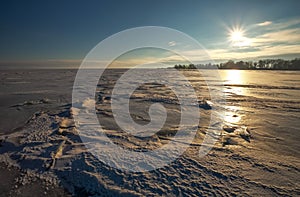 Beautiful winter landscape with frozen lake and sunset sky