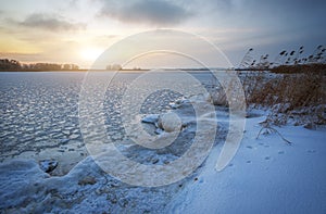 Beautiful winter landscape with frozen lake and sunset sky