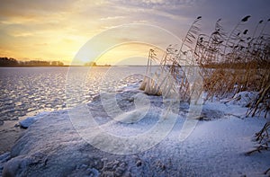 Beautiful winter landscape with frozen lake and sunset sky.