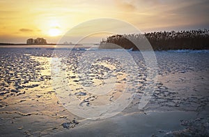 Beautiful winter landscape with frozen lake and sunset sky.