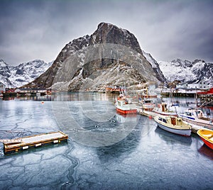 Beautiful winter landscape of harbor with fishing boats and traditional Norwegian rorbus