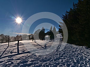 Winter landscape with hiking path on Schauinsland in the Black Forest hills, Germany with snow whirled up by the strong wind. photo