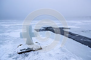 Beautiful winter landscape with Ice Cross on frozen river on foggy morning IV