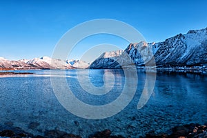 Beautiful winter landscape, lake with snowy mountains with serene blue sky, natural travel outdoor background, Lofoten Islands