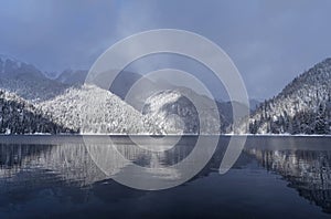 Beautiful winter landscape with mountain Ritsa lake and snow-covered trees along the shore. Tourism and winter holidays