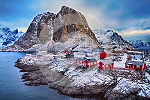 Winter landscape of picturesque fishing village with red rorbus in the mountains of Lofoten islands