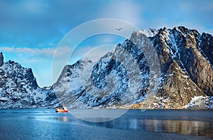 Beautiful winter landscape of picturesque mountains with fishing boat in Lofoten islands