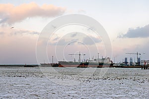 Beautiful winter landscape with ship in cargo port fuel terminal at sunset time., Ventspils, Latvia