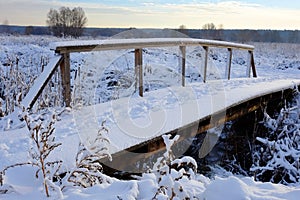 Beautiful winter landscape. Small wooden pedestrian bridge under the snow