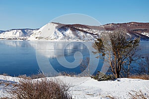 Beautiful winter landscape. Snow-capped mountains are reflected in the unfrozen Angara River