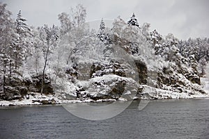 Beautiful winter landscape with snow-covered trees, flowing river and rocks. Snow forest and winter background. Fairytale winter