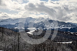 Beautiful winter landscape with snowy mountains. Winter scene. Snowy mountains peaks, hills, valley, slopes and forest. Landscape