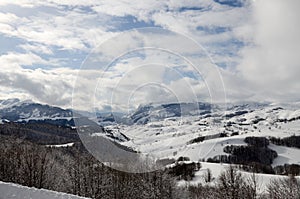 Beautiful winter landscape with snowy mountains. Winter scene. Snowy mountains peaks, hills, valley, slopes and forest. Landscape