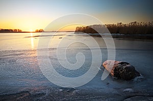Beautiful winter landscape with stump in the ice and sunset