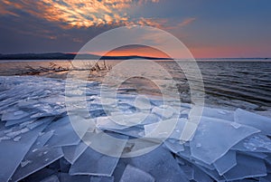 Beautiful winter landscape with sunset fiery sky and frozen lake. Composition of nature