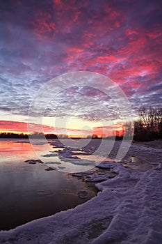 Beautiful winter landscape with sunset sky and frozen lake