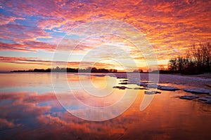 Beautiful winter landscape with sunset sky and frozen lake