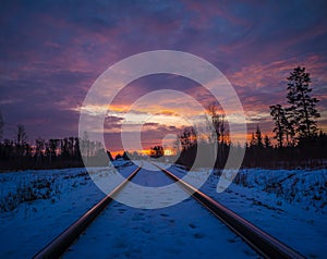 A beautiful winter landscape with train tracks during sunset.