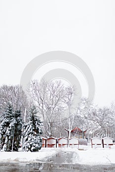 Beautiful winter landscape, trees and closed Christmas market wooden stalls covered with snow