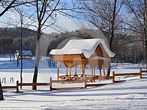 Beautiful winter landscape with a wooden pergola covered with a thick layer of snow on a Sunny frosty day