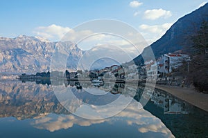 Beautiful winter Mediterranean landscape - mountains, blue sky with white clouds and reflection in the water. Montenegro