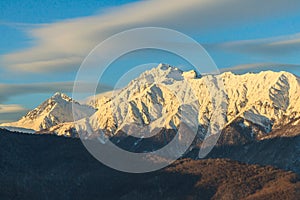 Beautiful winter mountain landscape of Main Caucasus ridge with scenic snowy Chugush mountain peak and blue sky at sunset