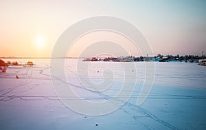 Beautiful winter panorama: landscape, a frozen river covered with ice against a sunset and an unusual sky.