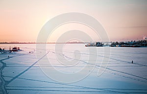 Beautiful winter panorama: landscape, a frozen river covered with ice against a sunset and an unusual sky.