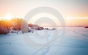 Beautiful winter panorama: landscape, a frozen river covered with ice against a sunset and an unusual sky.