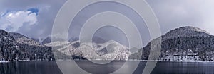 Beautiful winter panorama with mountain Ritsa lake and snow-covered trees along the shore.