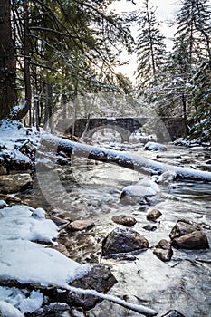 Beautiful winter river scene in the forest as snow covers rocks