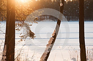 Beautiful winter scene. Sunset at the frozen lake covered with snow