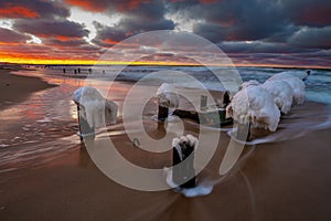 Beautiful winter sea landscape. Ice breakwaters, waves and fiery sunset. Artistic photography