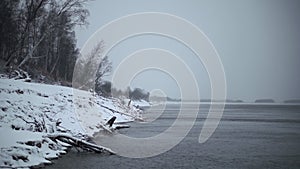 Beautiful winter sea shore with snow. Clip. Beach with sticks and trees on snowy winter day. Beautiful snow-covered lake