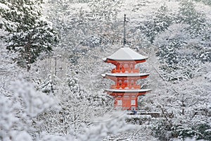 Beautiful winter season of Red Pagoda at Kiyomizu-dera temple surrounded with trees covered white snow background.