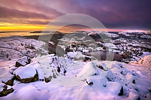Beautiful Winter sunrise with pink and purple hues reflecting on fresh covering of snow. Loughrigg Fell, Lake District, UK.