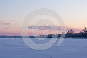 A beautiful winter sunrise scenery of frozen lake and forest. Colorful landscape with dawn skies