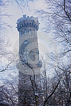 Beautiful winter view of frosted trees and rock at sunset, frozen lookout tower Sneznik