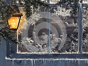 Beautiful winter window. Snow, icicles. Yellow lantern