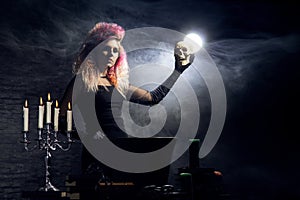 Beautiful witch making witchcraft on a smoky background. Halloween image.