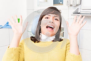 Beautiful woman acting terrify while sitting on dental chair