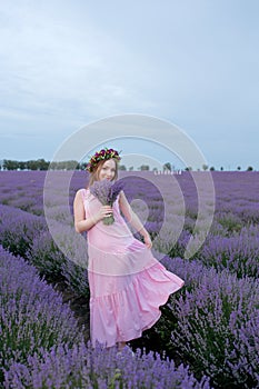 Beautiful woman admires a bouquet of lavender in a sunset, lavender field