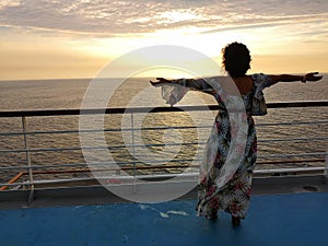 Beautiful woman admires sunset from cruise ship