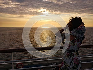 Beautiful woman admires sunset from cruise ship