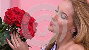 Beautiful woman admiring bouquet of red roses, surprise for Valentines day