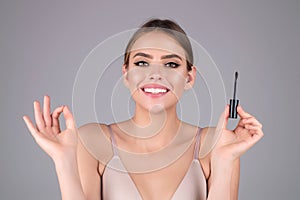 Beautiful woman applies brow gel with brows brush to her eyebrow. Studio portrait of young woman doing her eyebrow